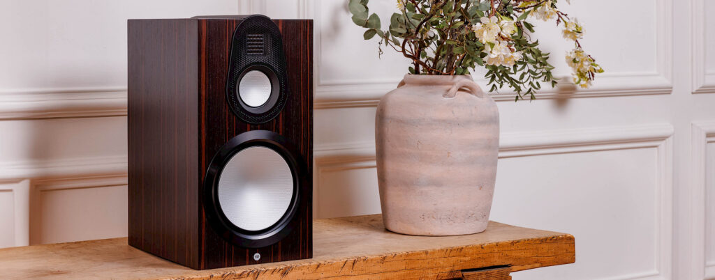 Close-up of Monitor Audio Gold 100 6G speaker showing woofers and textured Macassar Wood Veneer finish