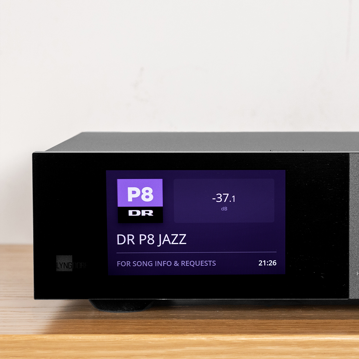 Lyngdorf TDAI-2210 streaming amplifier front view with touchscreen displaying album art